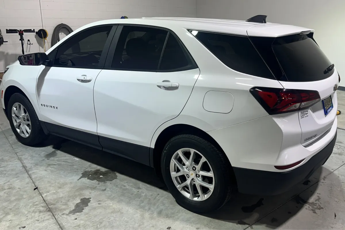 White Chevrolet Equinox with tinted windows, parked indoors in a clean space.