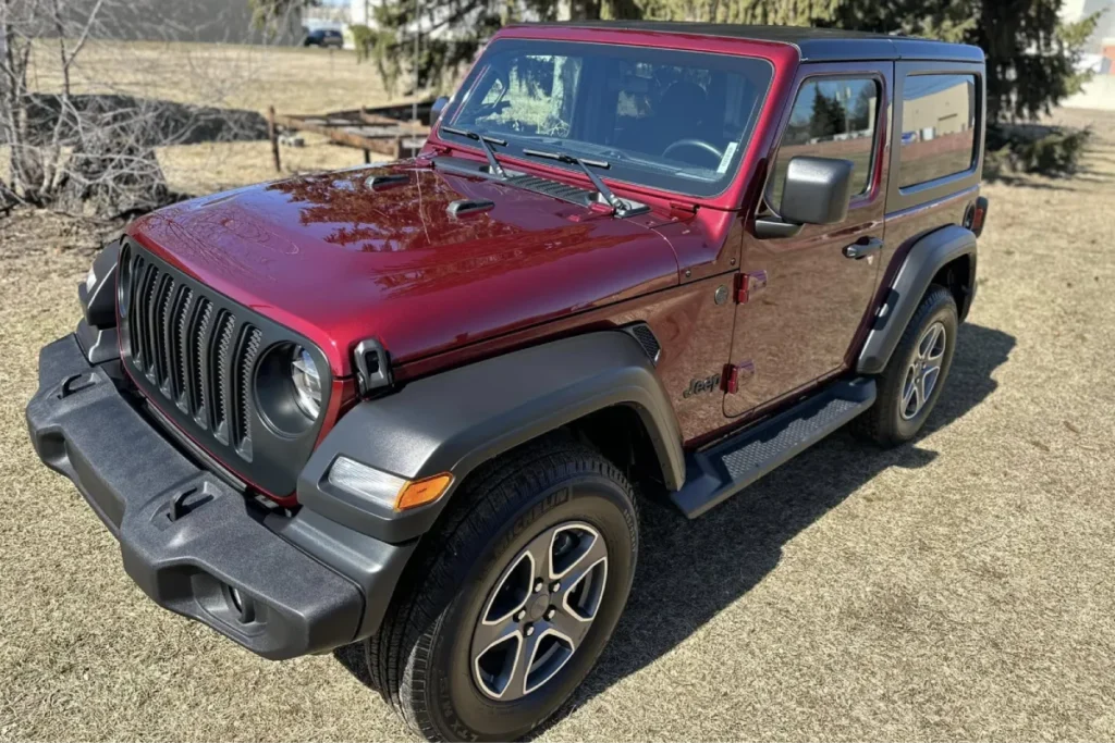 Red Jeep Wrangler parked outside with clear blue skies