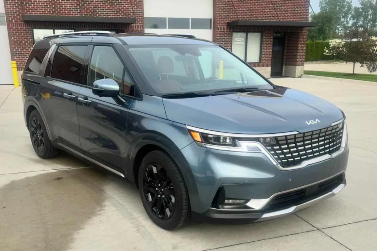 Angled side view of a Kia minivan with restored paint clarity after paint correction.