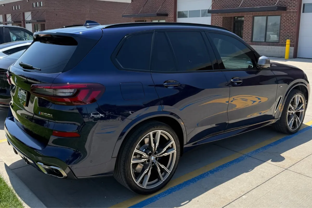 Rear side view of a blue BMW X5 protected with paint protection film.