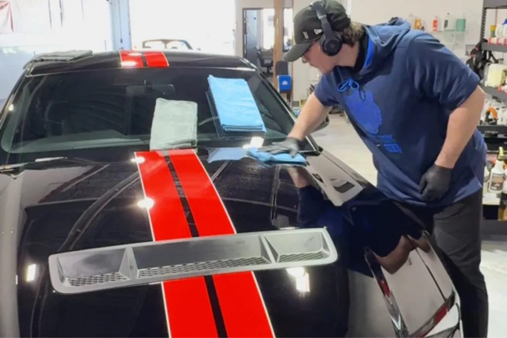 Technician performing paint correction on a black muscle car.